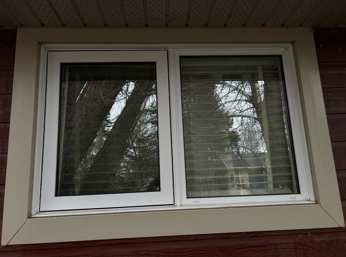 The same window clean, with the blinds and trees visible through the glass